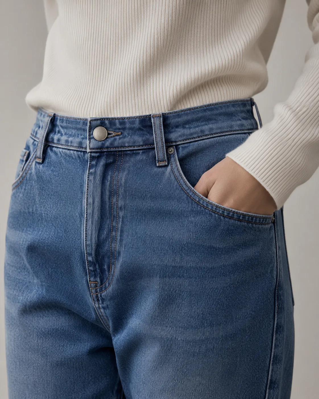 Denim waistband detail with a cream knit top