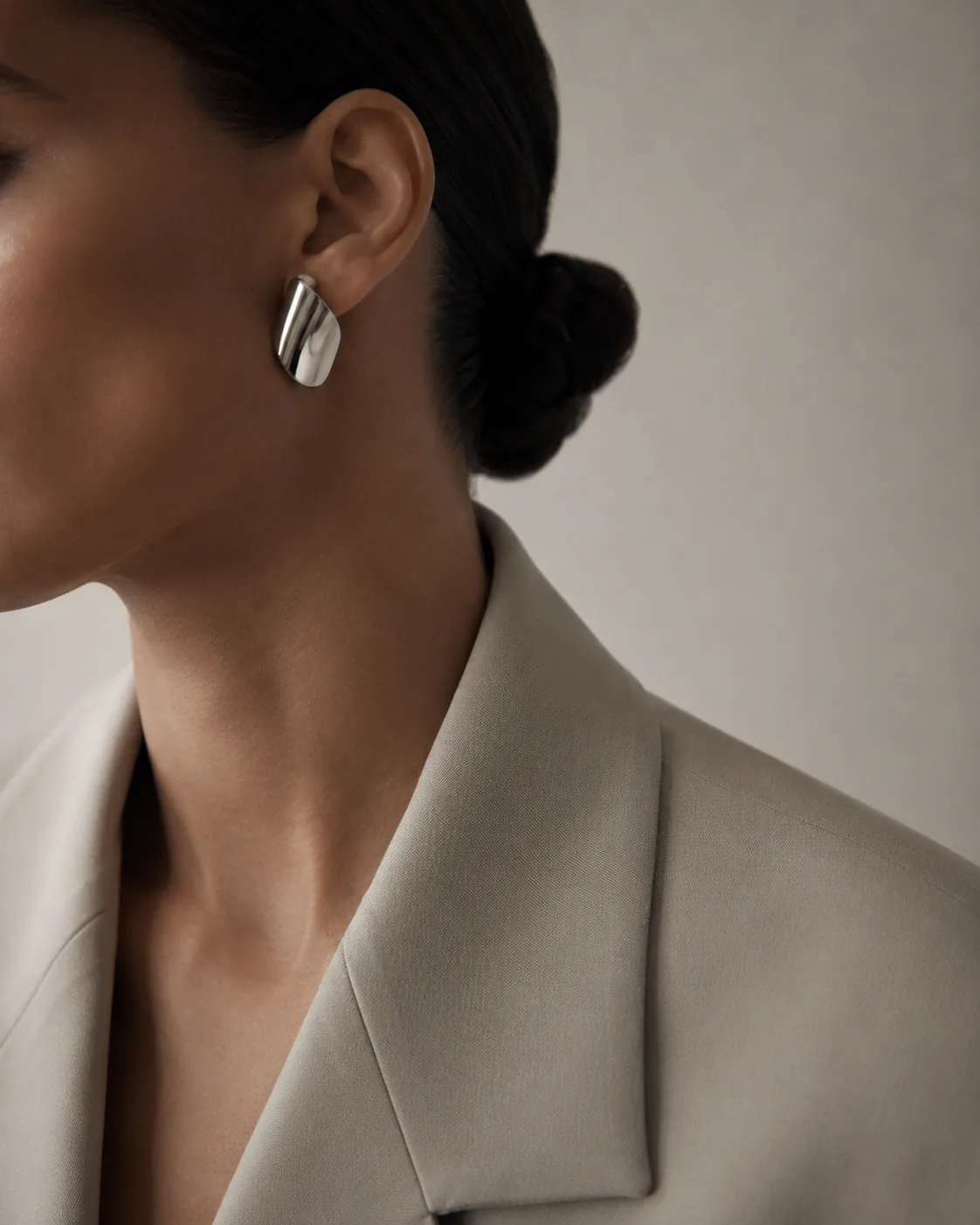 Sculptural silver earring with a tailored beige blazer